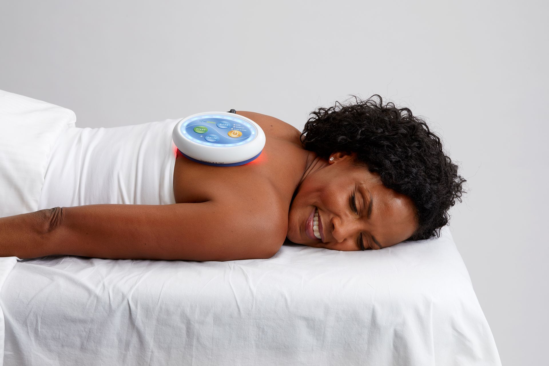 A woman is laying on a bed with a device on her back