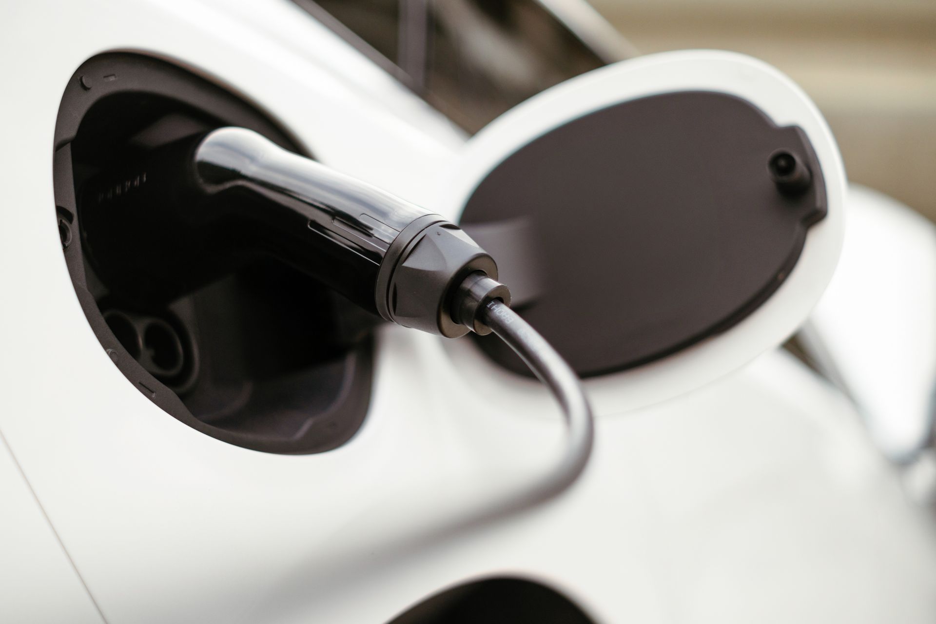 Electric car charging cable plugged into a white vehicle’s charging port