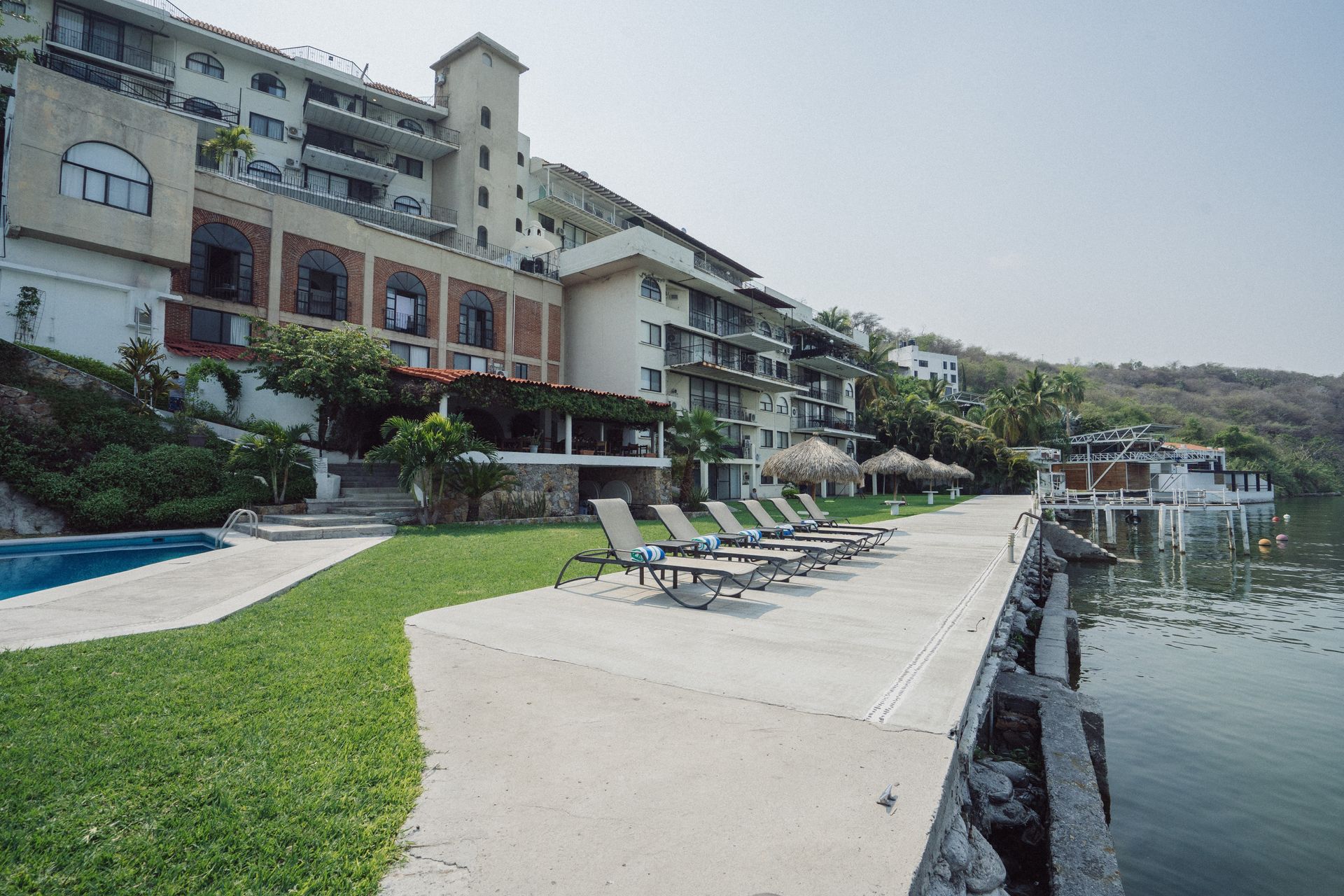 Hotel junto a un lago con camastros, piscina y muelle.