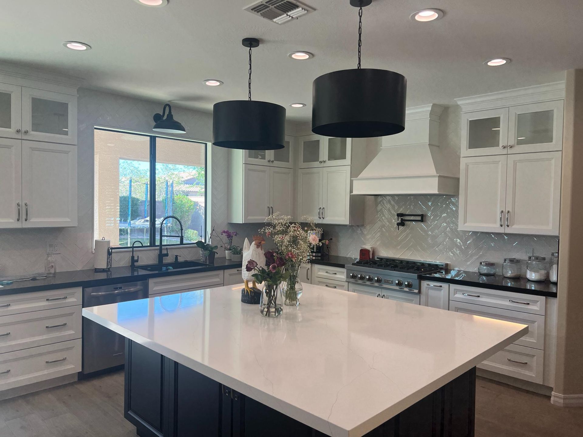 Modern white kitchen with a large island, black accents, and pendant lights.