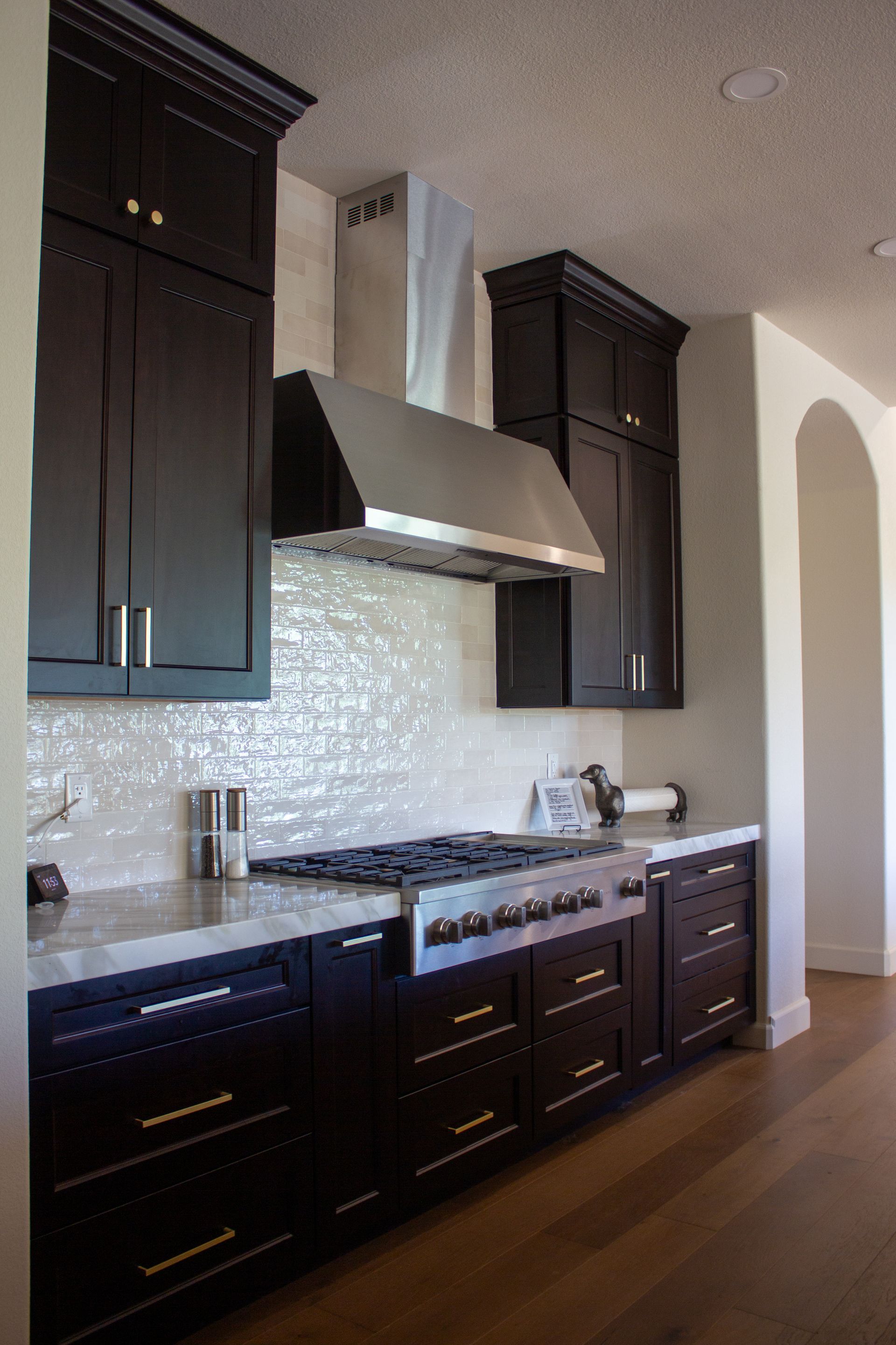 Black kitchen cabinets with white countertops and backsplash.