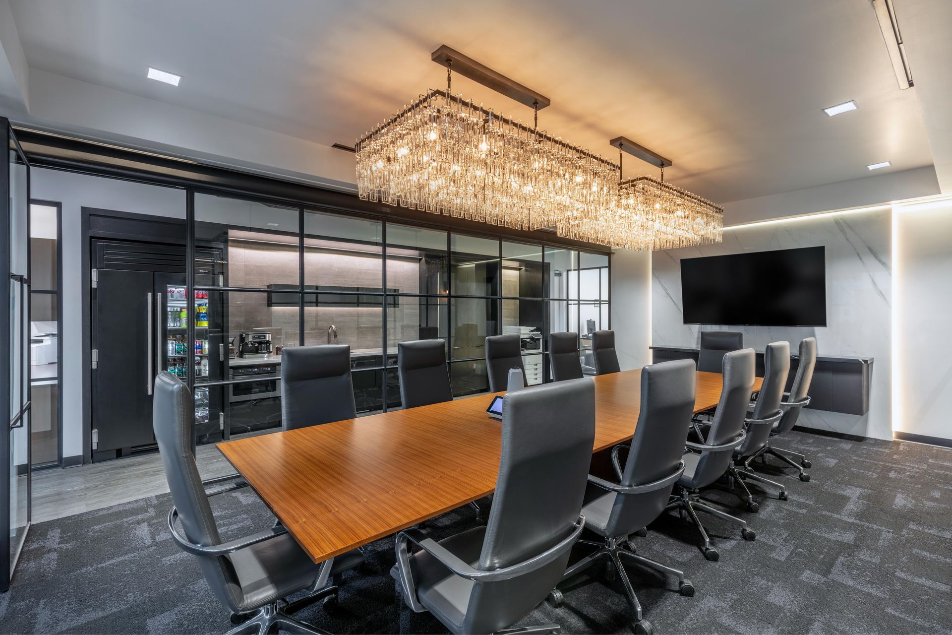Conference room with long wooden table, black chairs, and large chandelier.