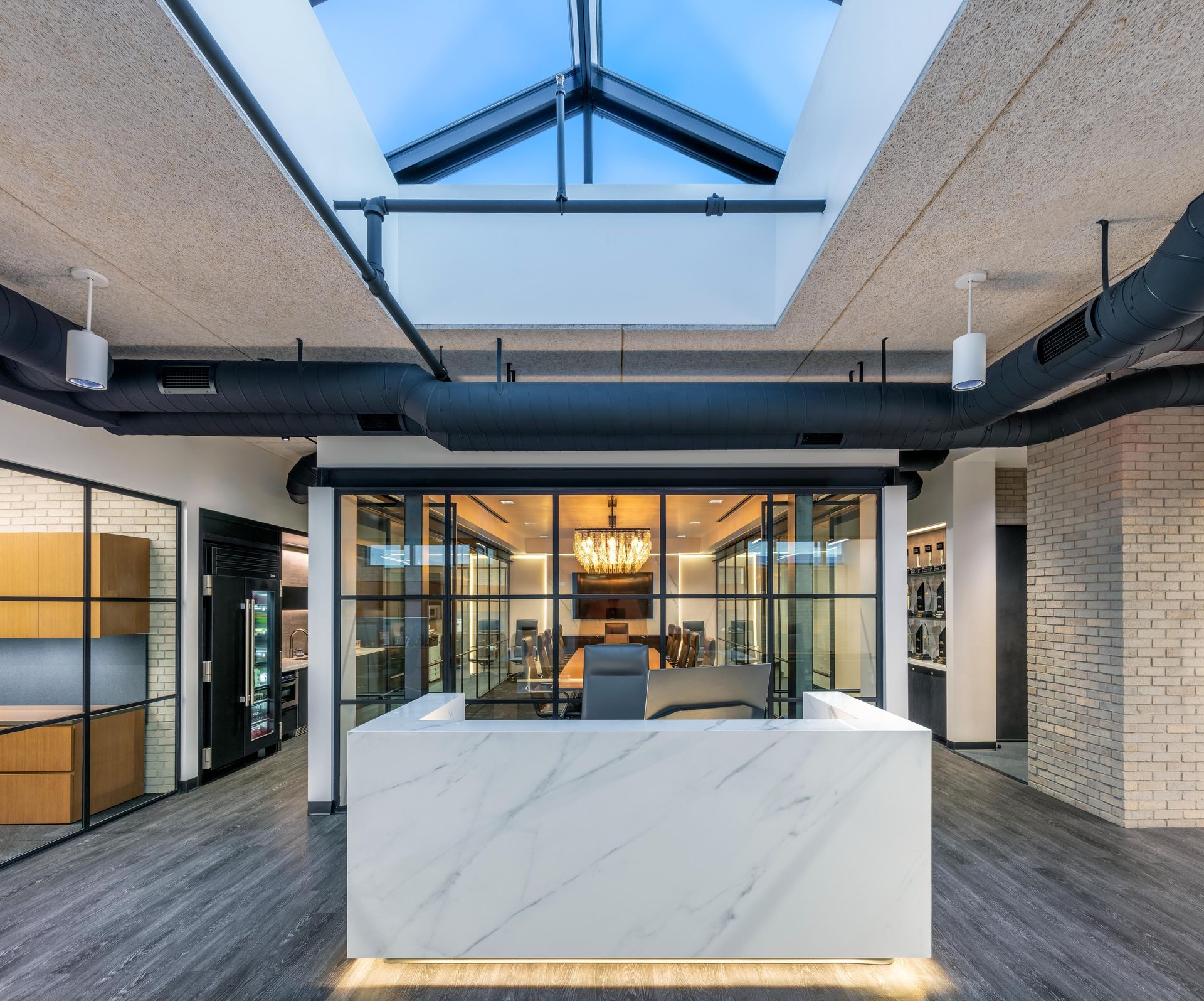 Modern office reception area with marble desk, glass-walled conference room, and skylight.