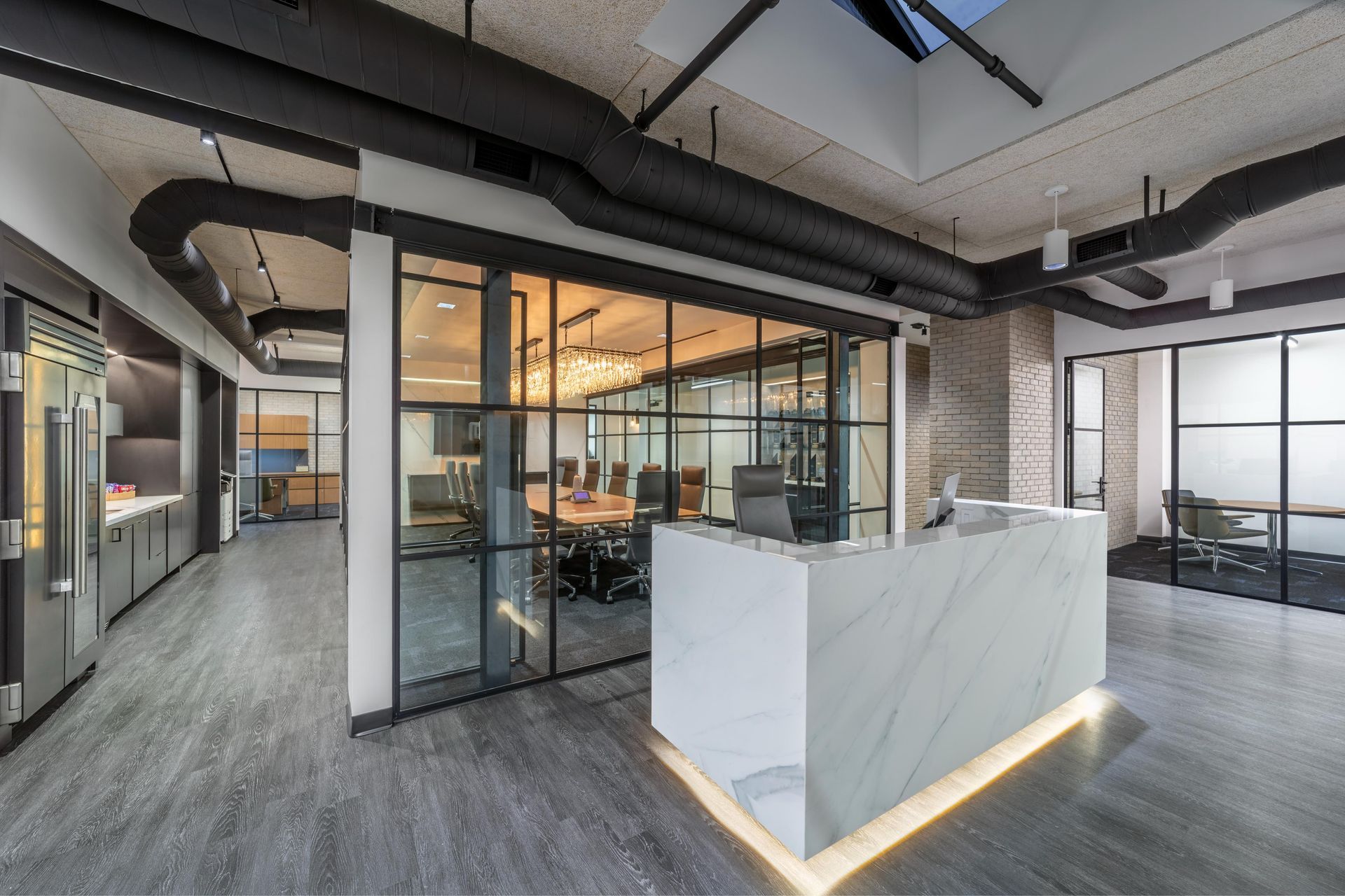Modern office interior with marble reception desk, glass-walled conference room, and grey flooring.