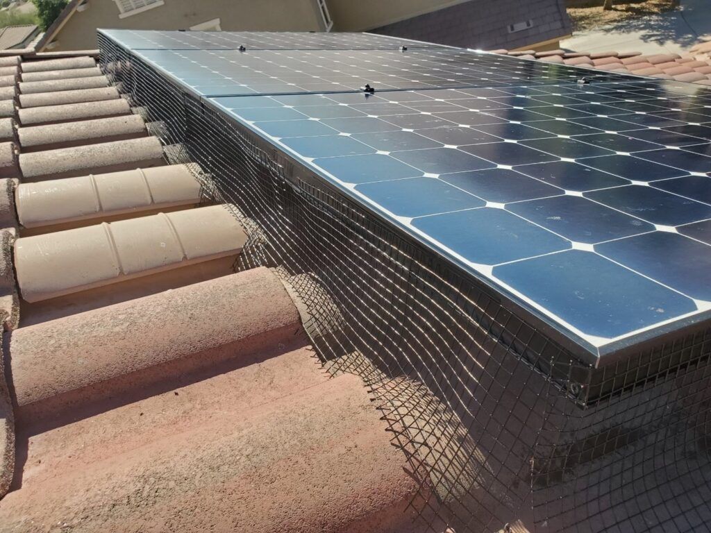 Two men are working on an air conditioner on the roof of a building.