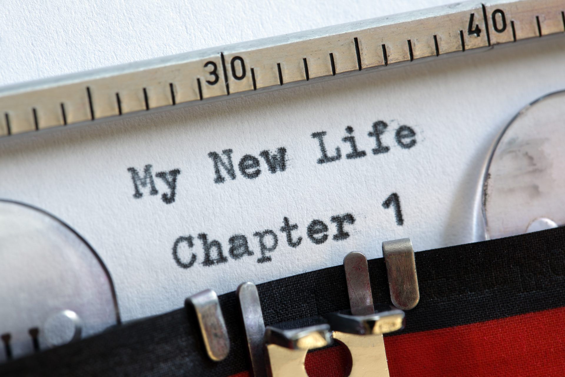 Typewriter with paper reading “My New Life Chapter 1” under a ruler close-up