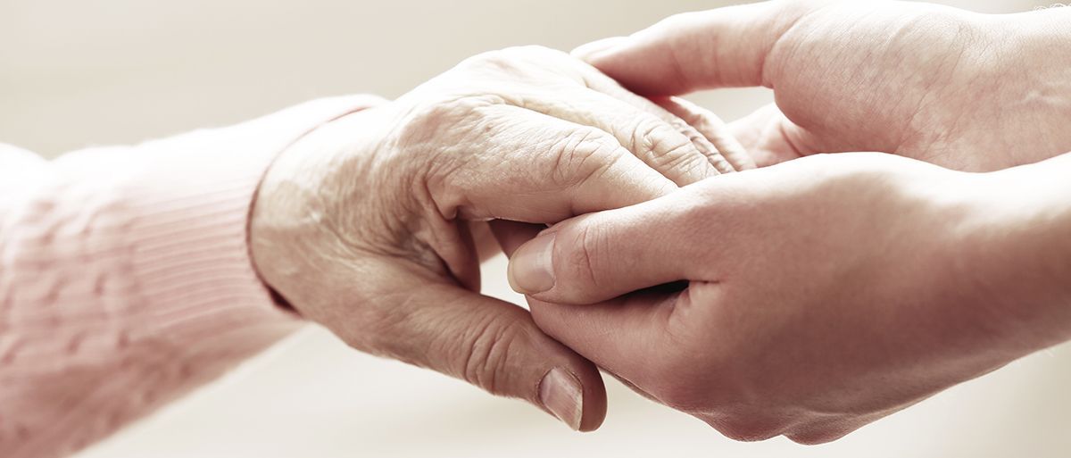Two hands gently holding each other in a soft, bright close-up