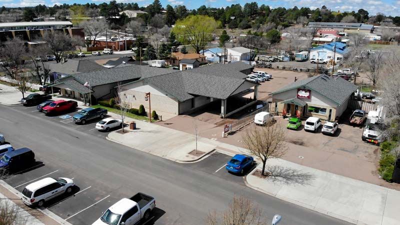 Aerial view of a suburban apartment complex with parked cars, trees, and nearby streets.