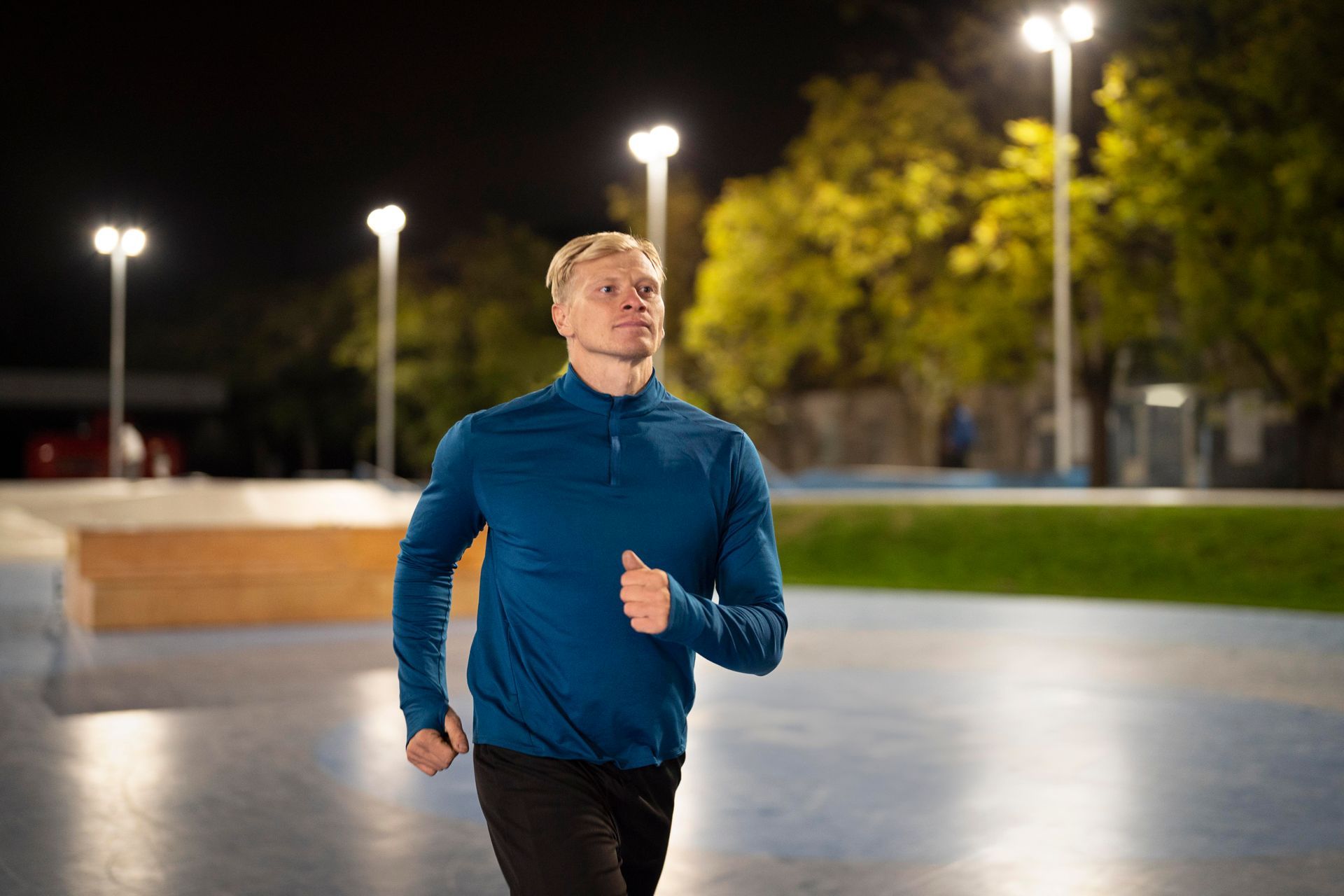 A man is running on a track at night.