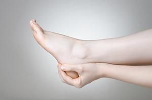 Person's hand holding heel of foot; possible pain or injury.