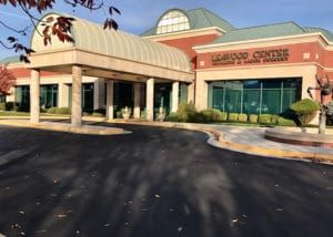 Exterior of the Leawood Centre, a red brick building with green glass windows. A covered entryway leads to the main entrance.
