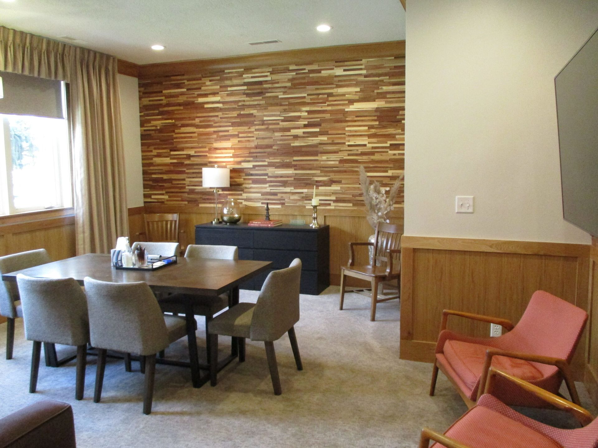 Dining room with a table and chairs, stone accent wall, and a window with curtains.