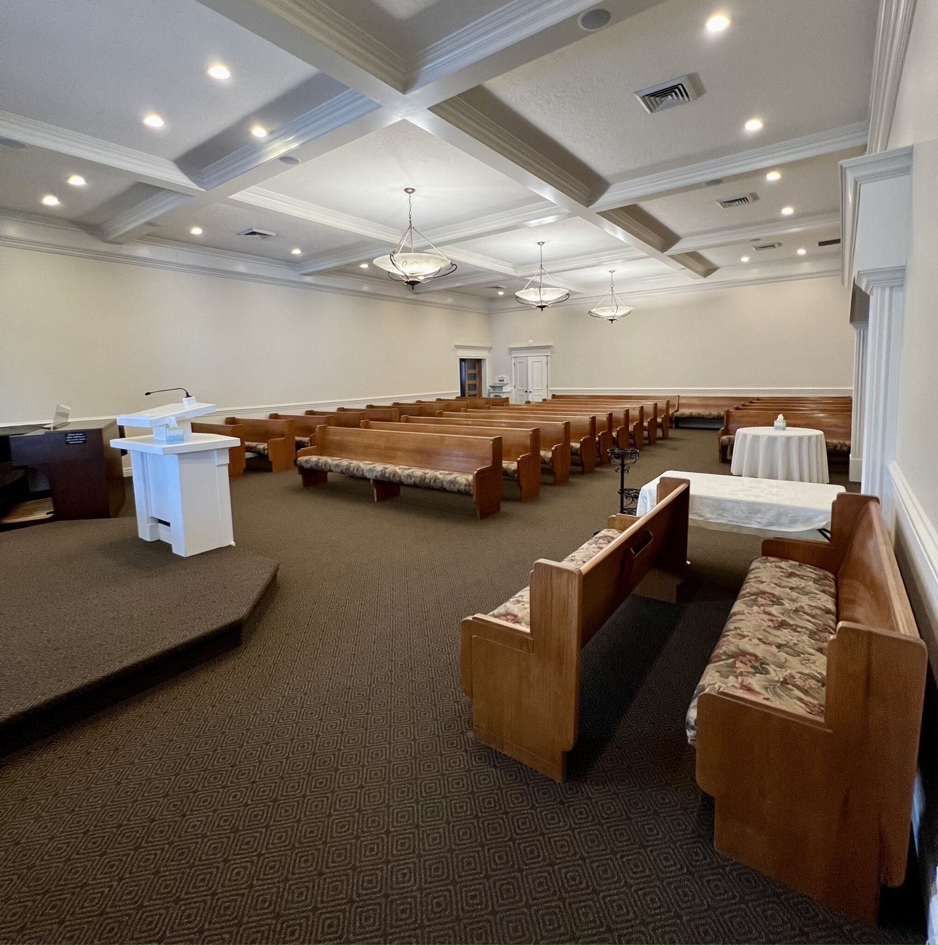 Empty banquet hall with rows of wooden chairs, carpeted floor, and white ceiling lights in a large meeting room