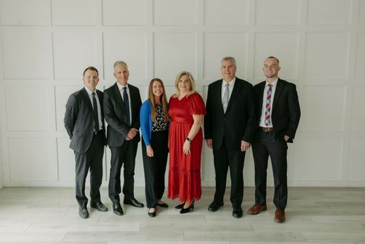 Five people standing in a bright room against a white paneled wall.