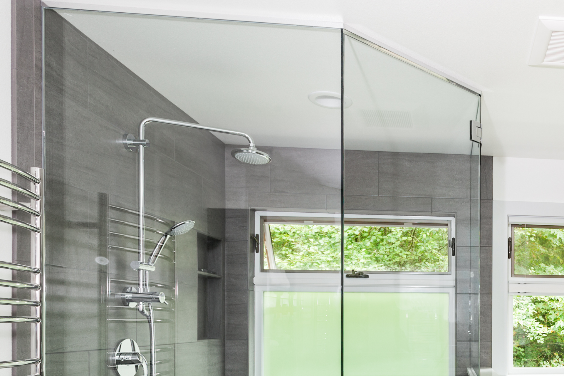 Modern shower with glass walls, gray tile, and chrome fixtures.