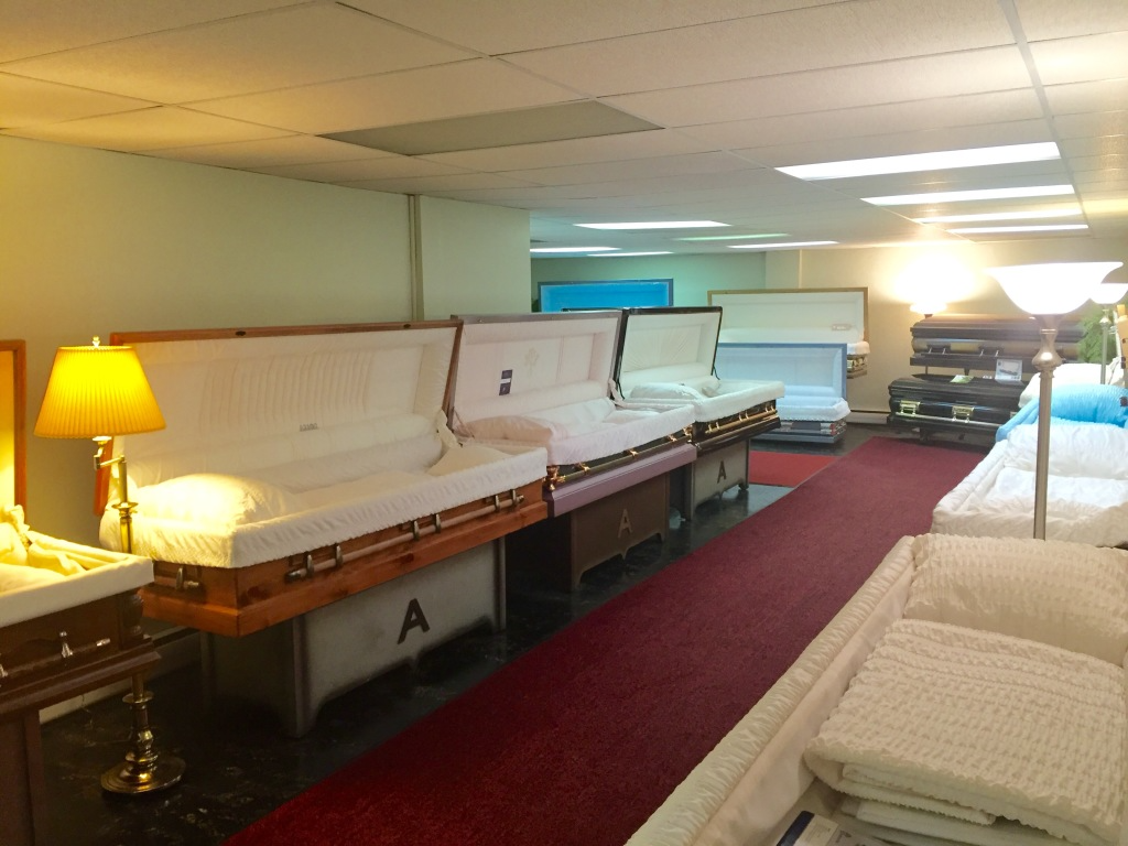 Showroom of upholstered church pews and sofas under fluorescent lights, with a lit table lamp on the left