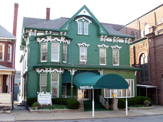 Green Victorian-style building with white trim and a covered entrance