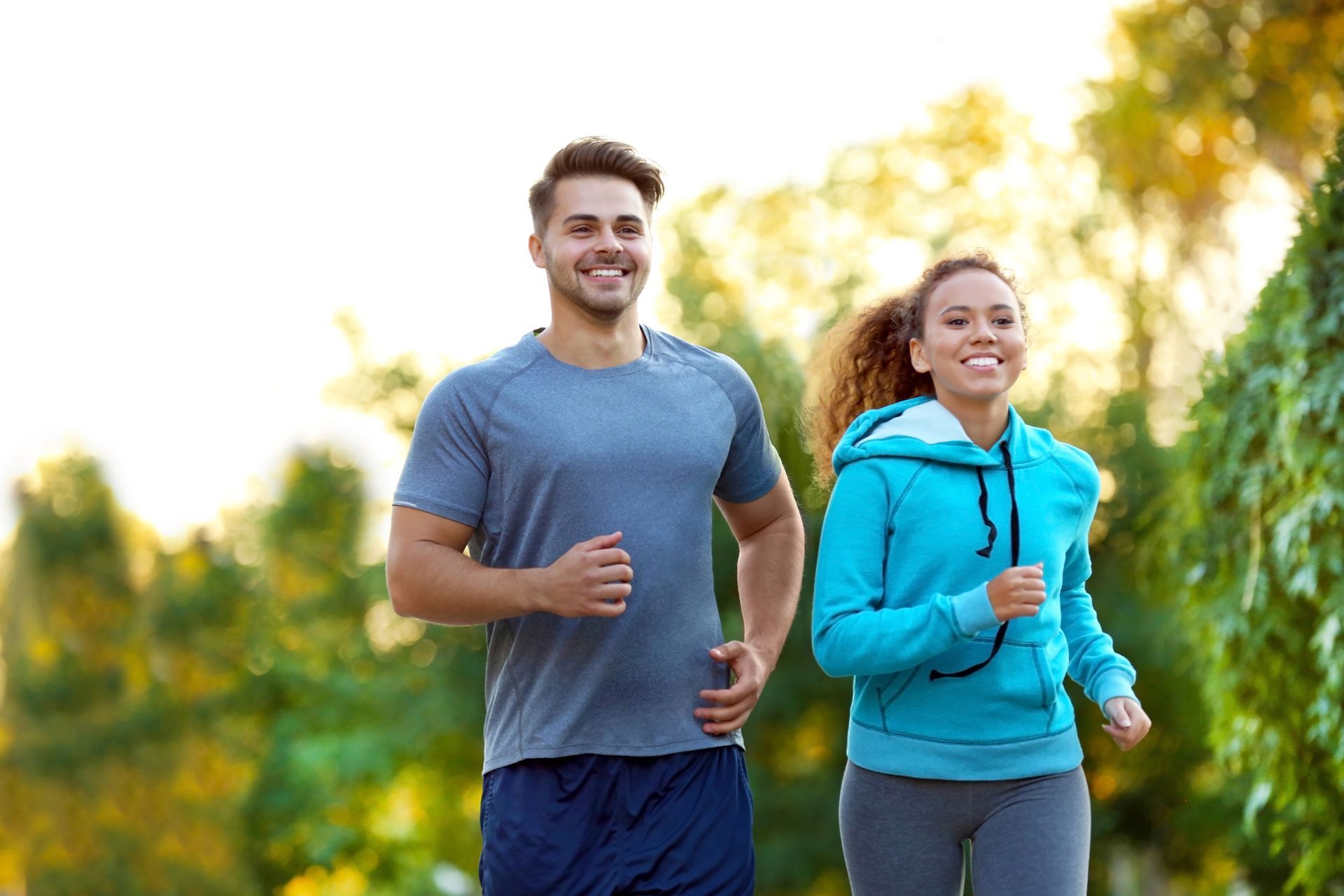 A man and a woman are jogging in a park.
