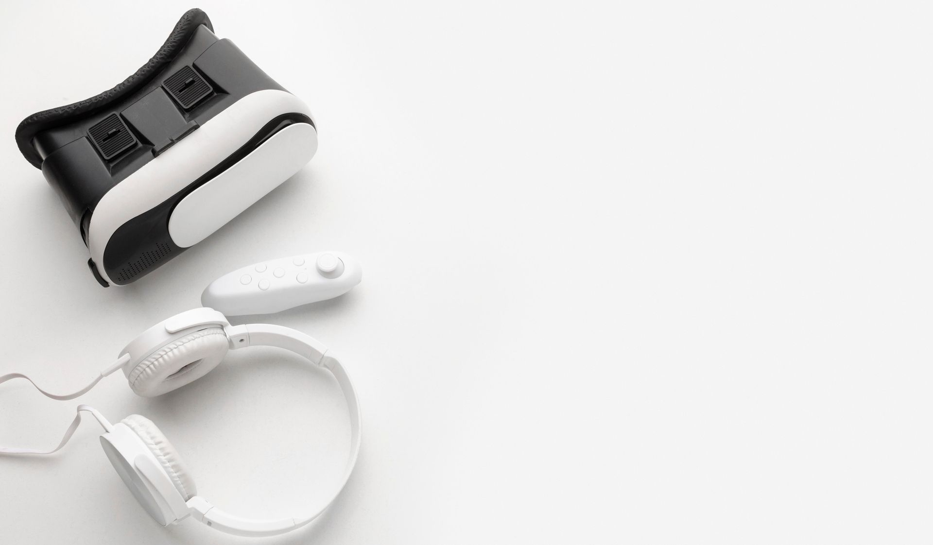 VR headset, controller, and headphones on a white surface.