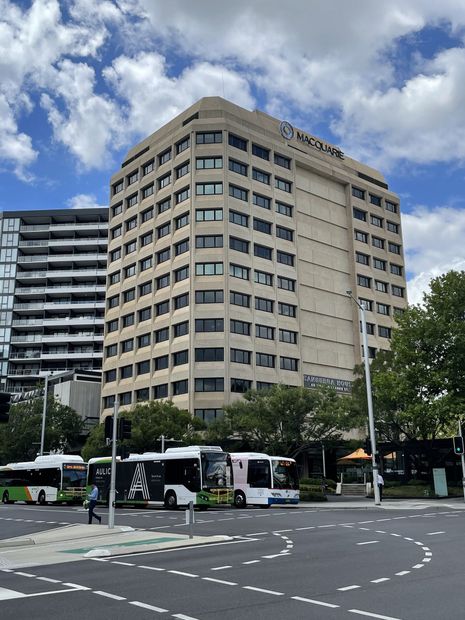 A group of buses are parked in front of a large building.
