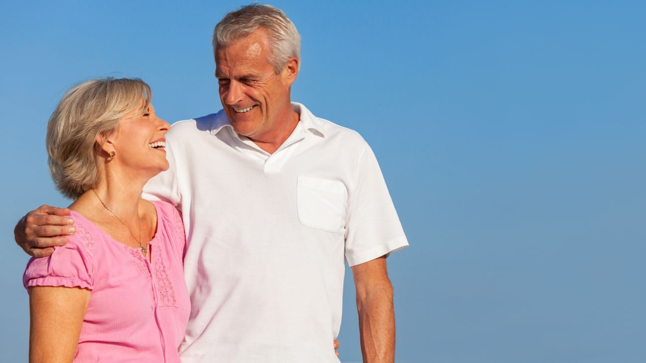 A man and a woman are standing next to each other on a beach.