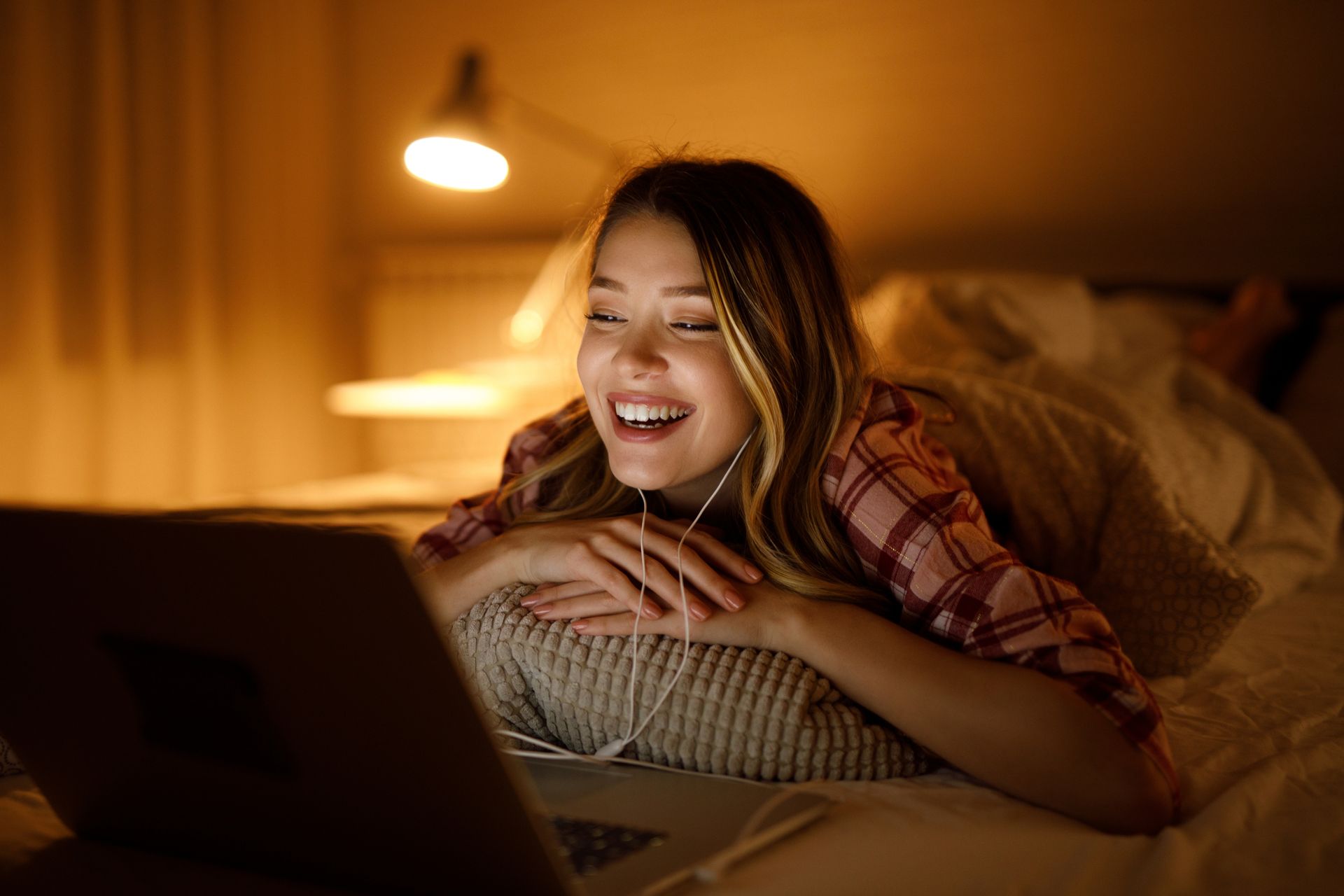 A woman is laying on a bed using a laptop computer.