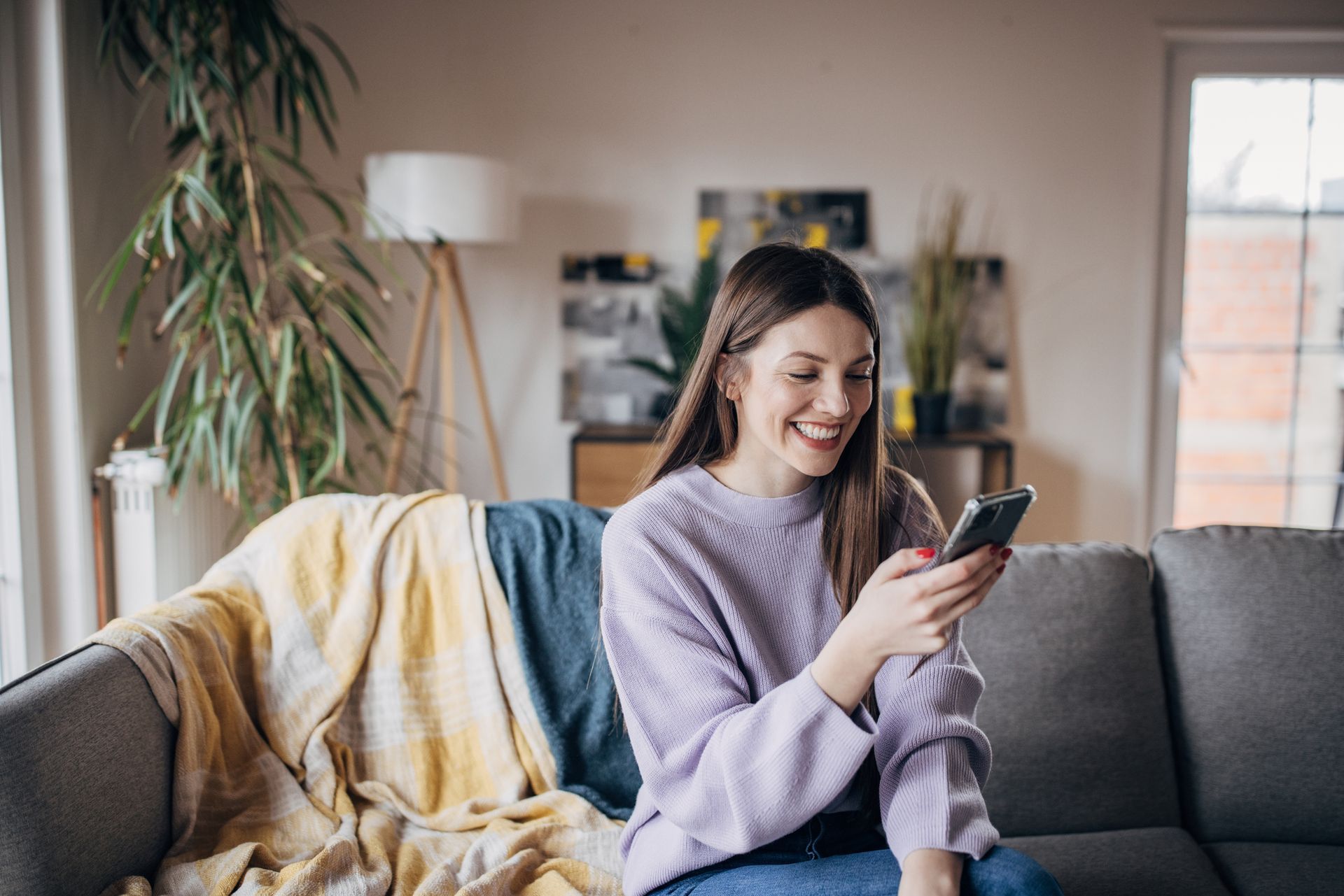 A woman is sitting on a couch looking at her cell phone.