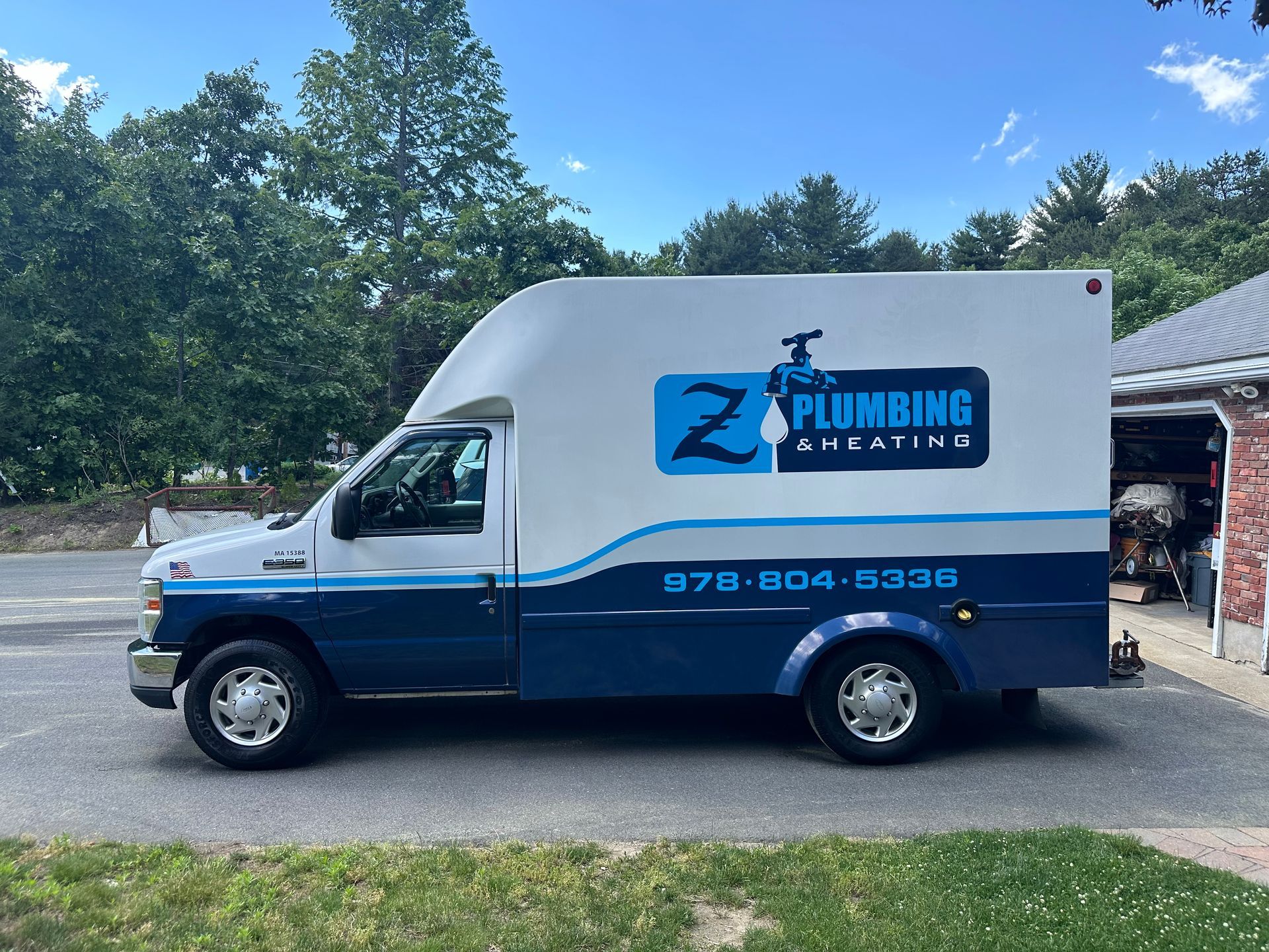 White and blue Z Plumbing & Heating work van parked on a driveway; 870-004-8338 phone number displayed.