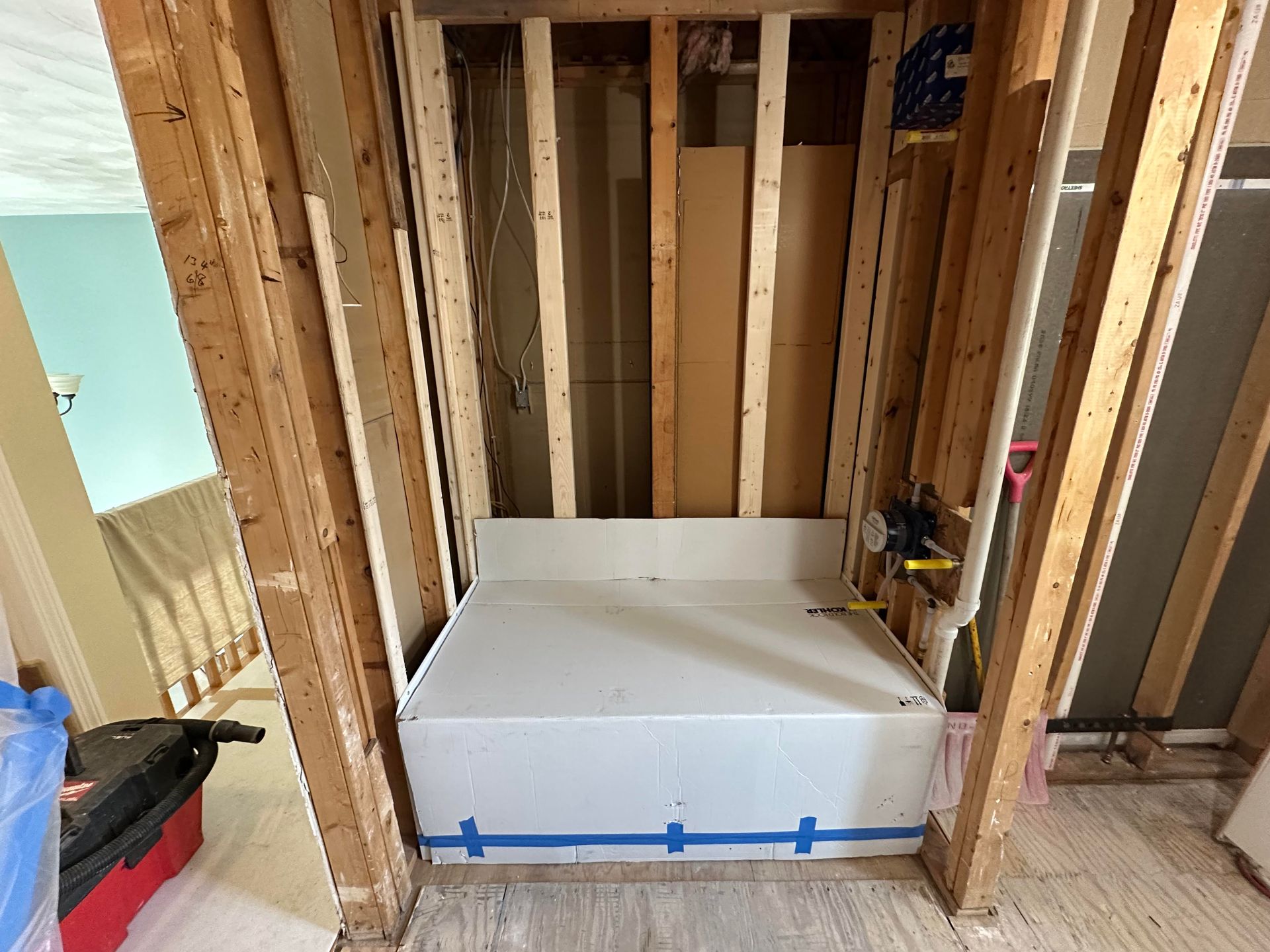 Construction site: A white bathtub base is installed between wooden studs.