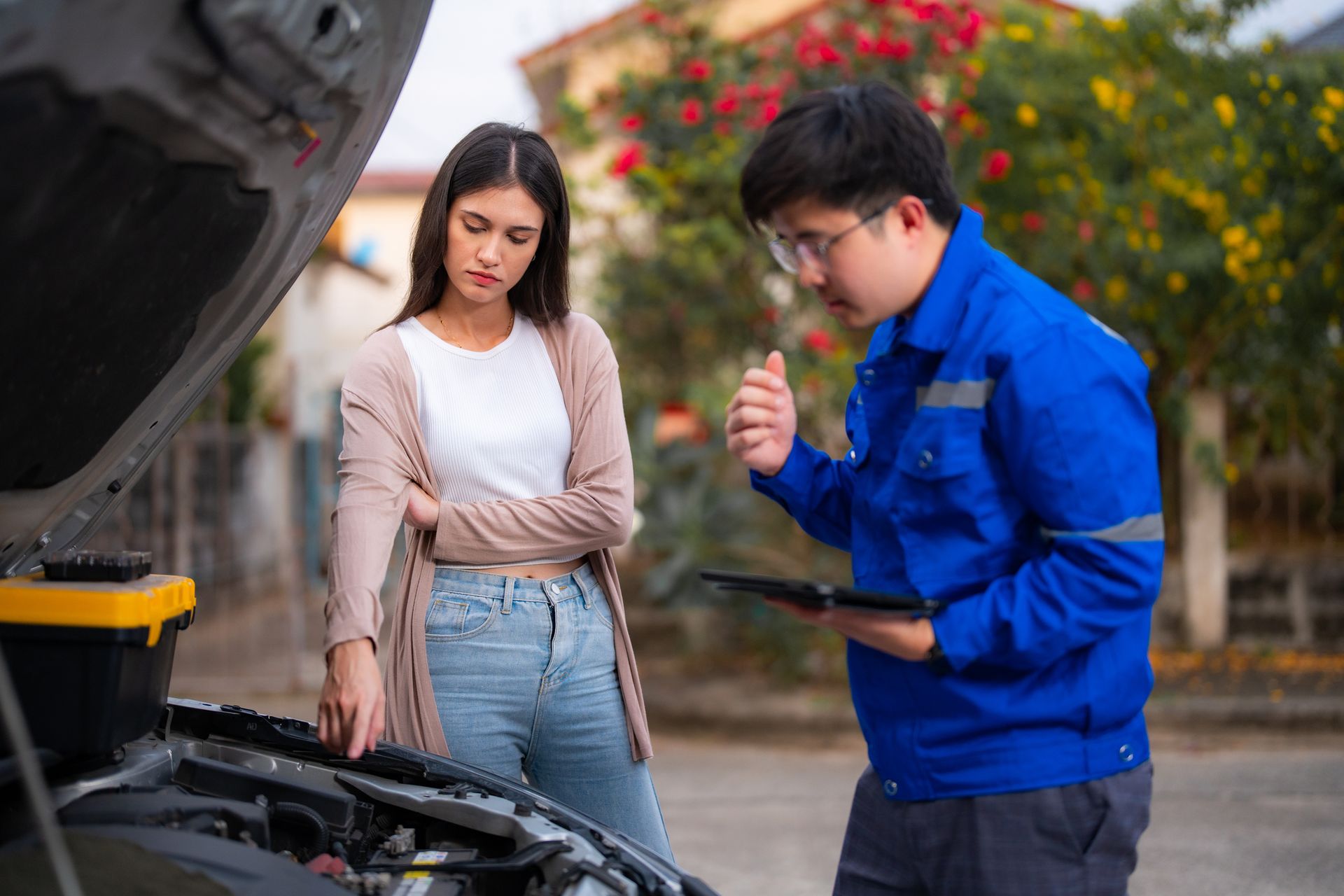 Mechanic with blue uniform fixing the car of a woman in the streets Mechanic with blue uniform fixing the car of a woman in the streets