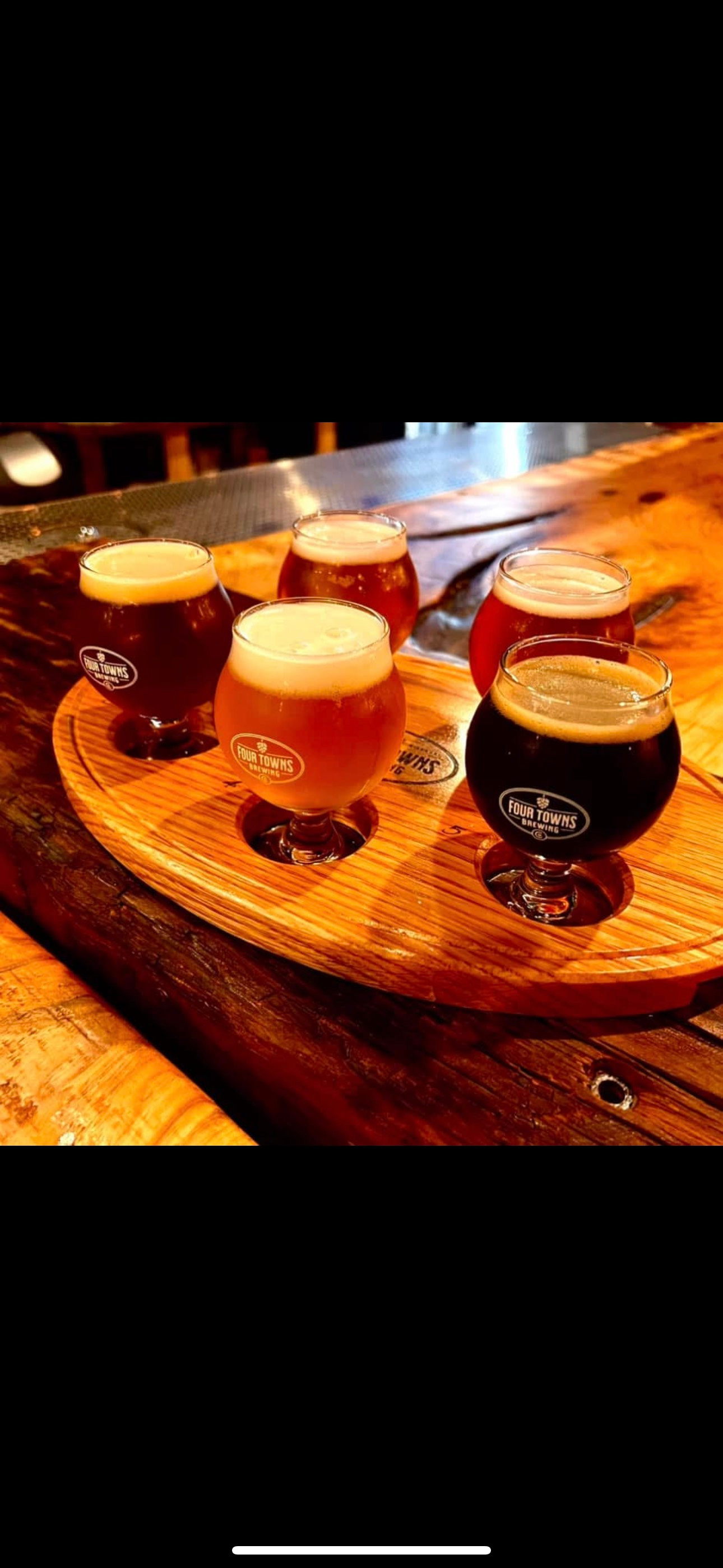 A wooden tray filled with different types of beer on a table.