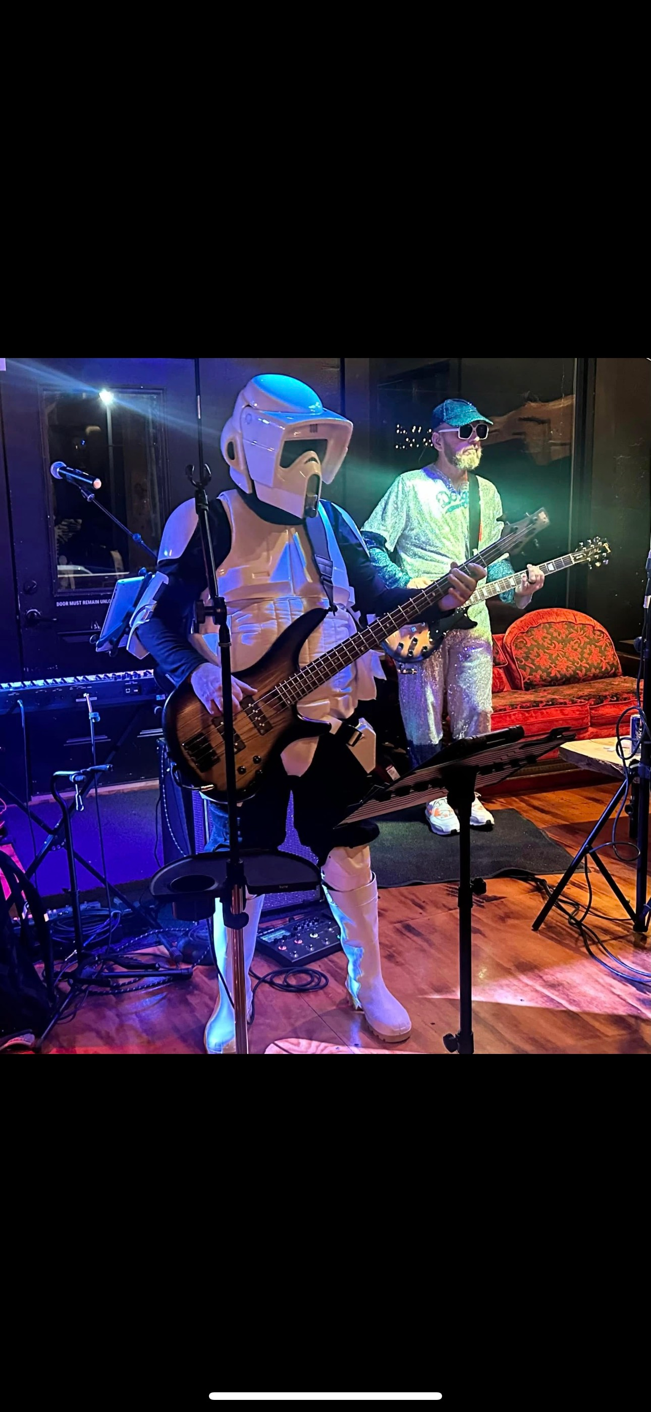 A man in a storm trooper costume is playing a guitar on stage.