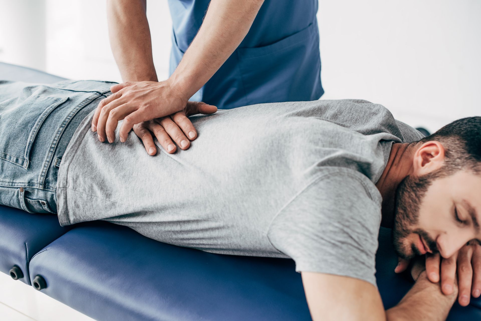 Massage therapist applying pressure to a man lying face down on a treatment table