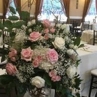 Pink and white rose centerpiece on a banquet table in a bright event venue