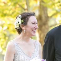 Smiling woman in a white dress with flowers in her hair at an outdoor event