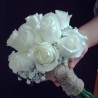 White rose bouquet with lace-wrapped handle and small baby's breath flowers, held in a hand