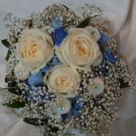 Bouquet of cream roses, blue flowers, and baby’s breath wrapped in white paper