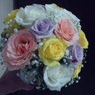 Bouquet of pastel roses in pink, white, yellow, and lavender with baby’s breath on a dark background