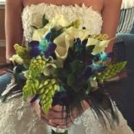 Person in a white dress holding a bouquet of blue, white, and green flowers
