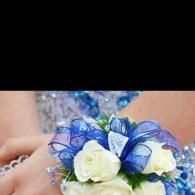 White and blue floral corsage with translucent blue ribbons on a beaded dress
