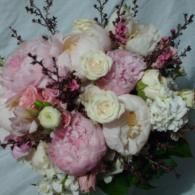 Pink and white floral bouquet with roses and carnations against a soft gray background