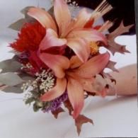 Pink and red flower bouquet with lilies and white filler flowers in a hand-held arrangement