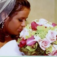 Person in a veil holding a bouquet of pink and white flowers, looking down thoughtfully.