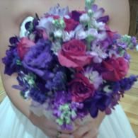 Person holding a bouquet of pink and purple flowers indoors