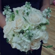 White rose bouquet with green accents held against a dark dress