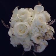 White rose bouquet with delicate pale lavender accents on a dark background