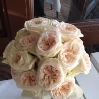 Bouquet of pale peach and cream roses arranged in a round, elegant cluster