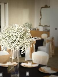 Elegant banquet table with white floral centerpieces, cream chairs, and soft candlelight in a reception hall
