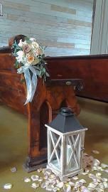 Wooden church pew decorated with flowers and a white lantern on the floor with scattered petals