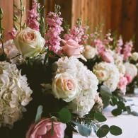 Rows of white and pink roses arranged along a wooden table